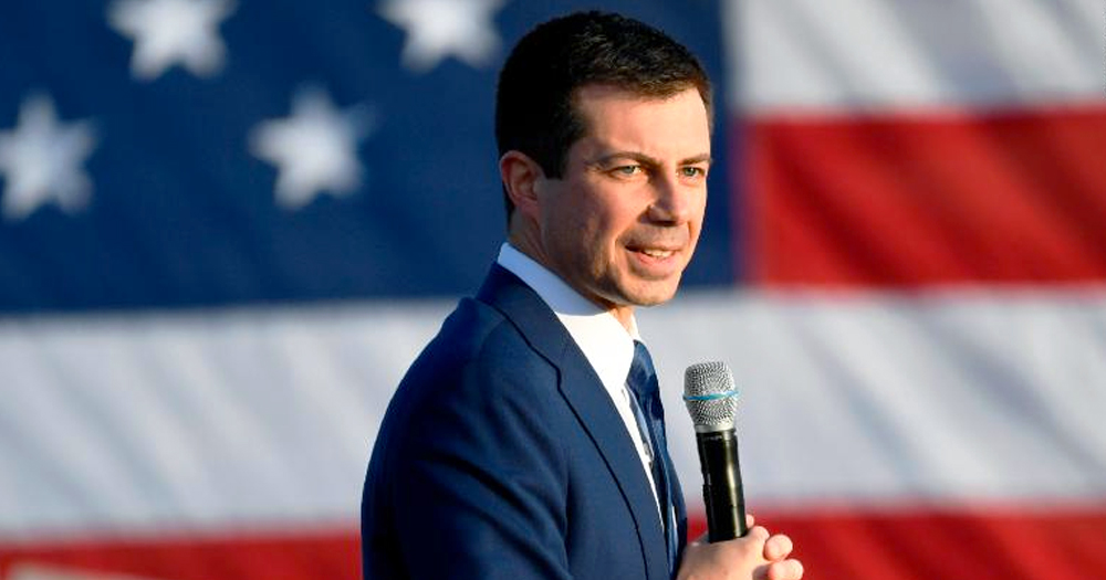 Pete Buttigieg holding a microphone. Behind him the American flag. Buttigieg is set to join the US cabinet