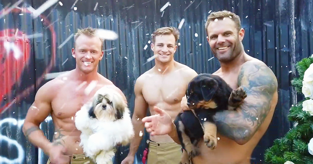 Three Australian firefighters holding puppies, shirtless, looking at the camera