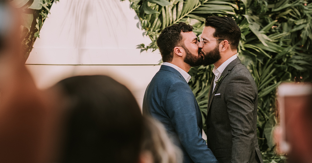 Two men kissing at a wedding