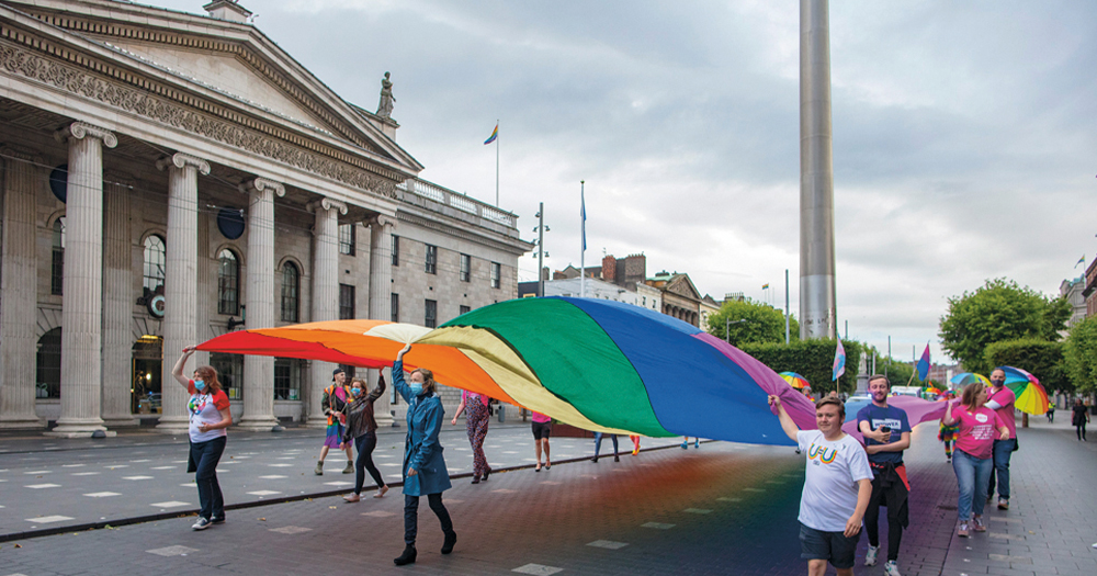 A group of people march down O'Connell Street carrying a gigantic Pride flag