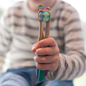 Sustainable Stocking fillers: guy holding bamboo toothbrushes