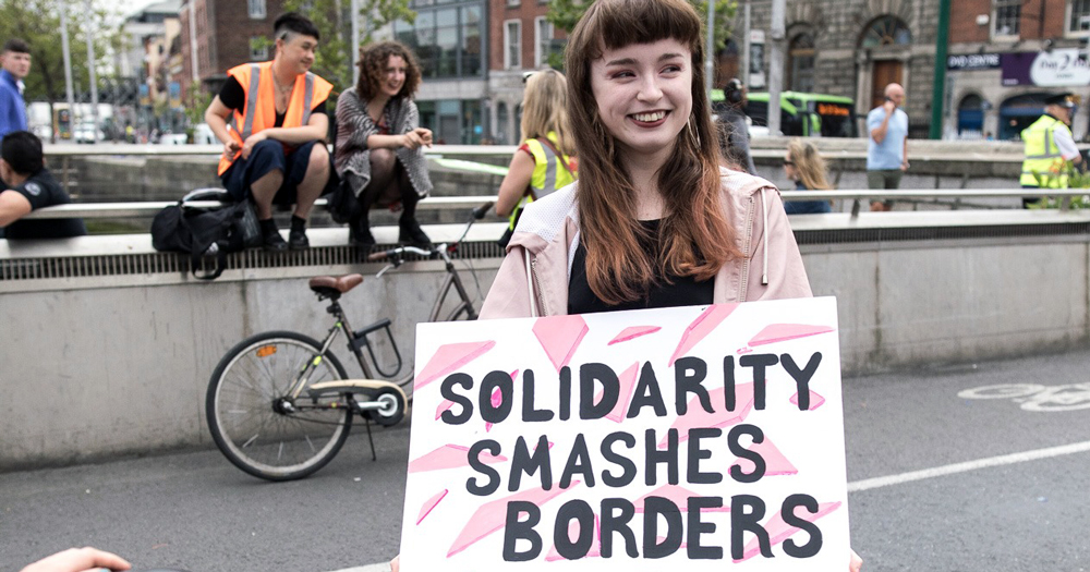 Trans Solidarity: Person holding a sign that says Solidarity Smashes borders