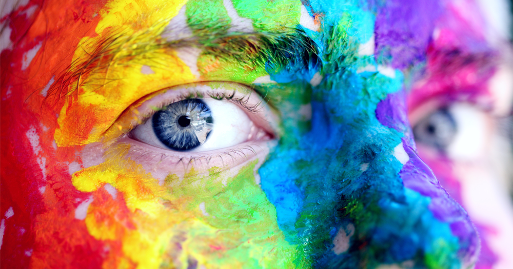 man with rainbow colour face paint zoomed up to just his nose and eyes