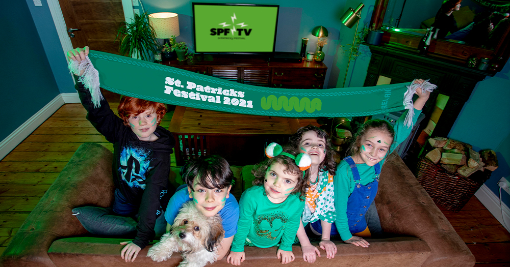 Five children hold up a green banner in their sitting room