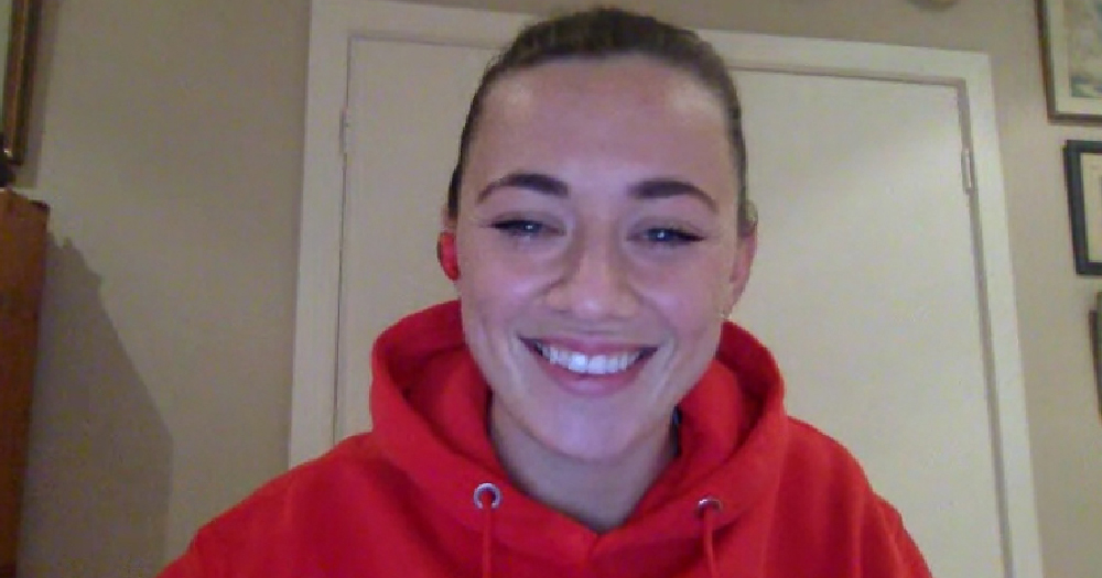 A smiling young woman on a zoom call