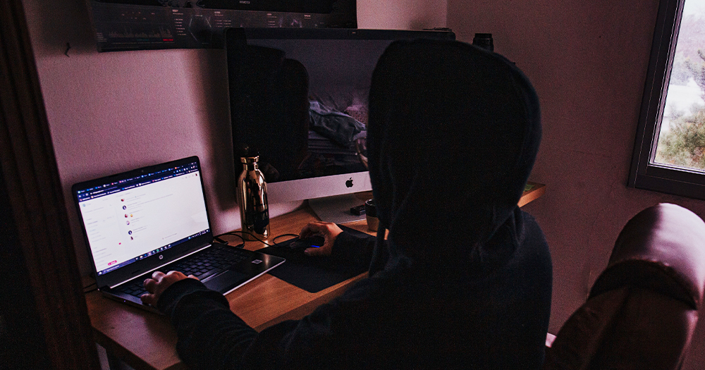 A person in a hoodie sitting at a laptop