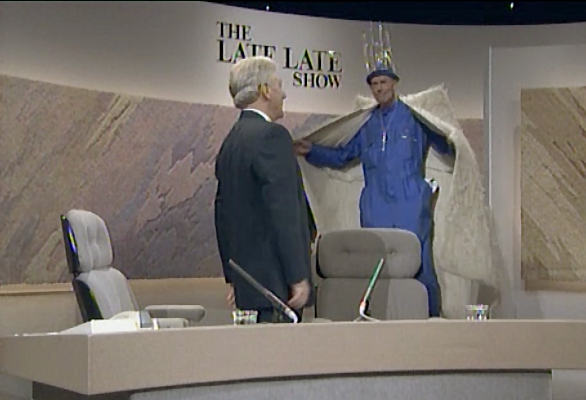 From RTÉ queer Archives: A man in a large fur coat and a crown greets another on the set of a TV studio