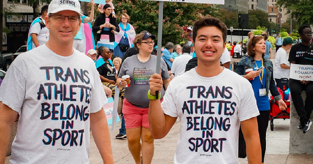 Two young men wearing t-shirts supporting trans athletes