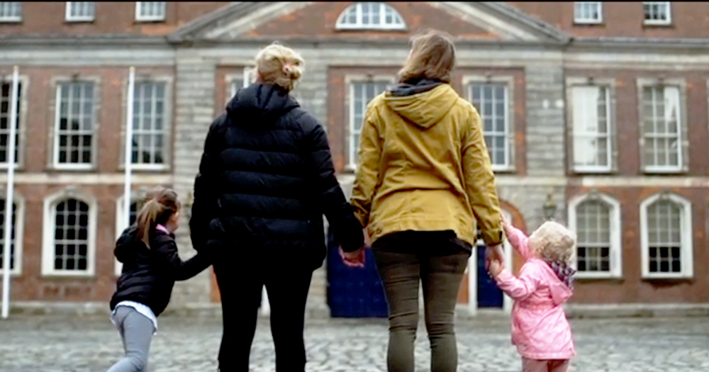 Two women holding two little girls' hands outside a building