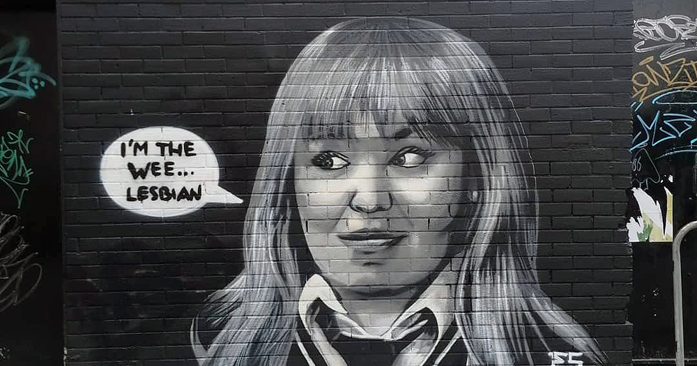 A mural on a wall featuring a girl in a school uniform saying 'I'm the wee lesbian'