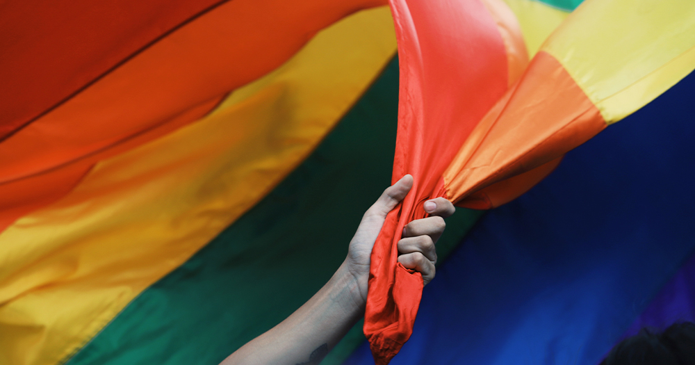 A hand clutching a huge rainbow coloured sheet