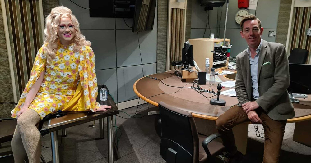 A drag queen and an interviewer sitting in a radio studio