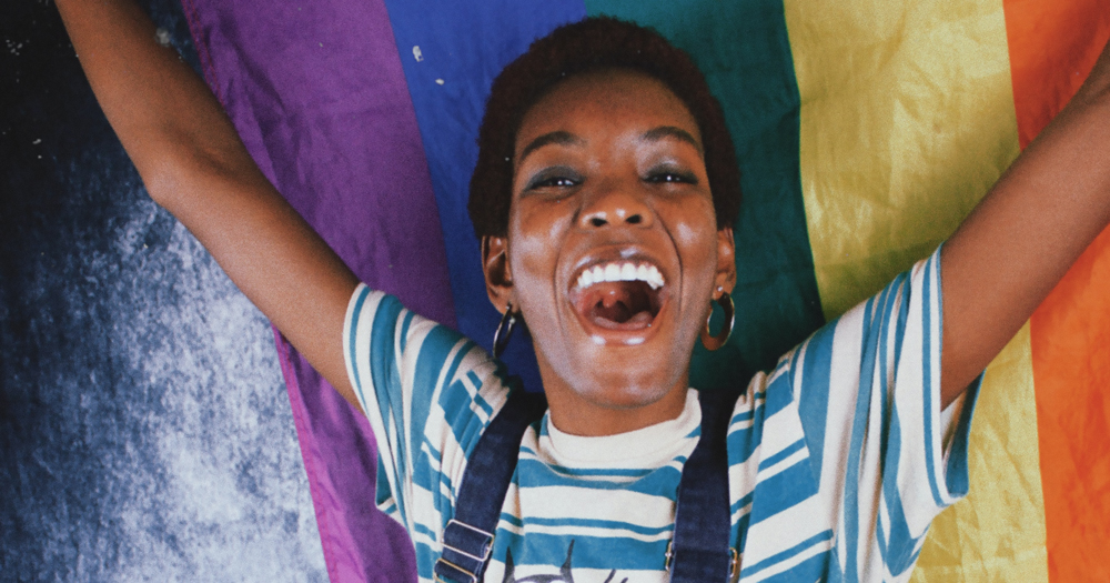 A joyous woman holding up a rainbow coloured fabric