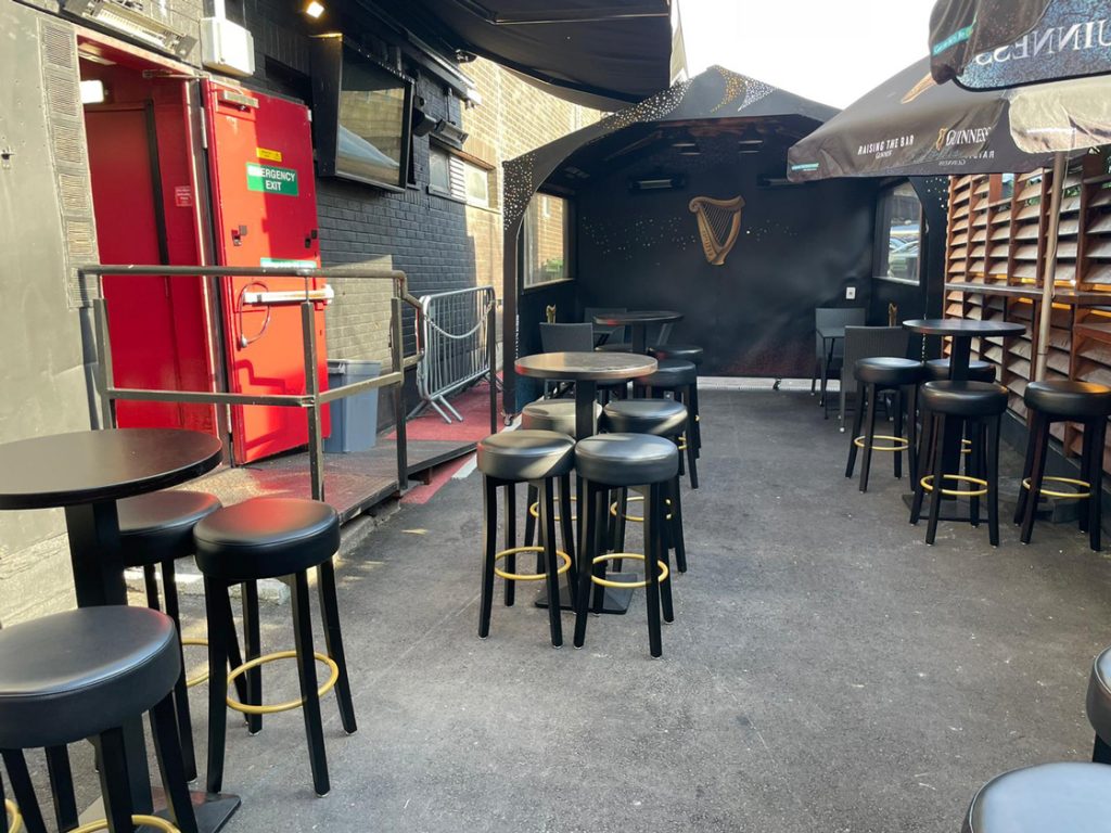 Outside sitting area of The George with bacl seats and rainbow flags. The iconic gay bar will be reopening in June.