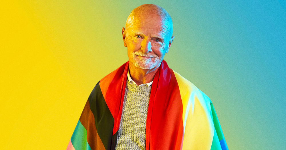 An older man wrapped in a Pride flag