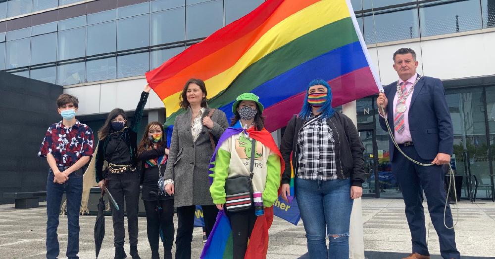 Waterford Pride Flags: group of LGBTQ+ activists pose in front of rainbow flag
