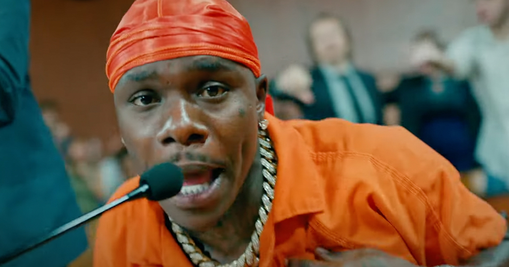 A man dressed in a prison uniform raps into a microphone