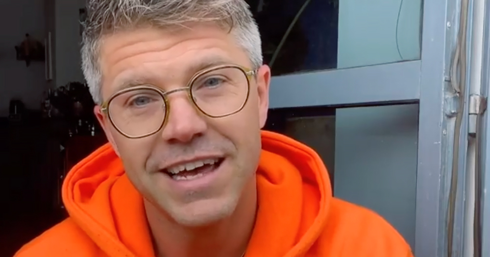 Close up of Darren Kennedy in an orange jumper and glasses. The TV presenter shared how he was victim of casual homophobia recently