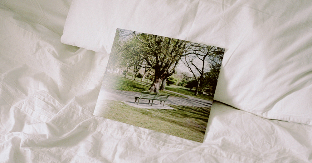 A photo of a bench in a park lying on an unmade bed
