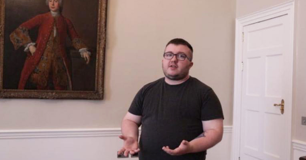 A young man with glasses speaking in an art gallery