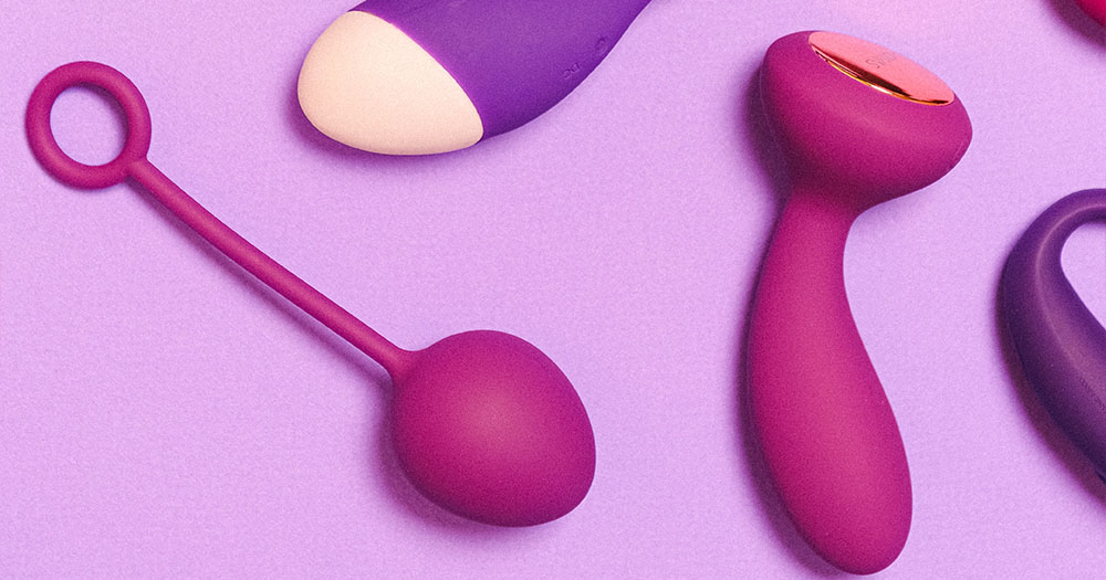 Multiple pink and purple sex toys for beginners are pictured on a lilac background, some toys are only partially in the image.