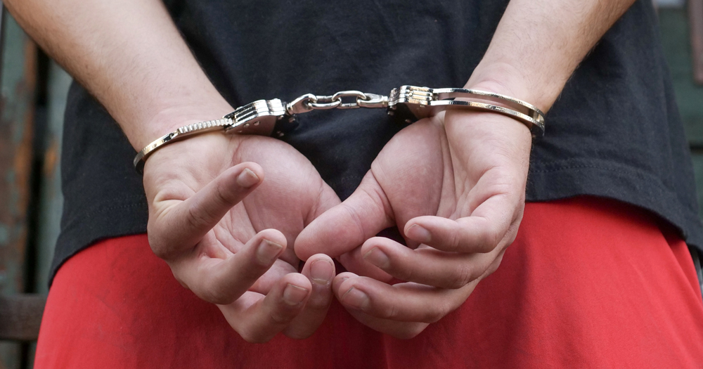 Image of a persons hands behind their back in handcuffs