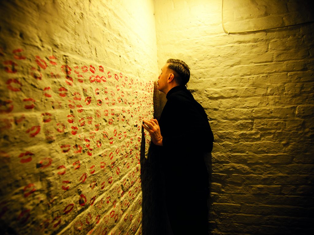 Image of Francis Fay kissing a wall in Kilmainham Gaol
