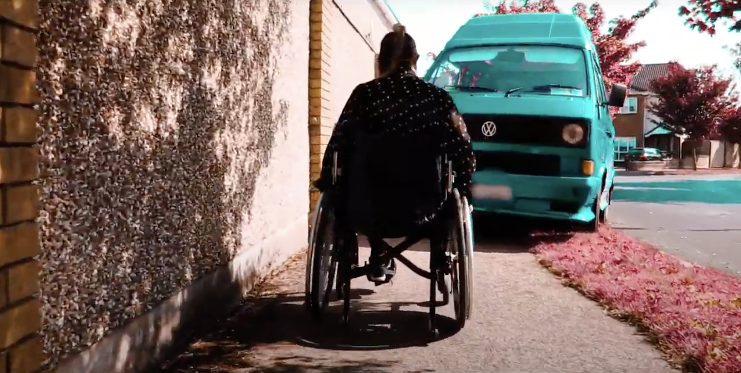 Person in a self-propelled wheelchair approaching a van parked on the footpath, blocking the wheelchair access