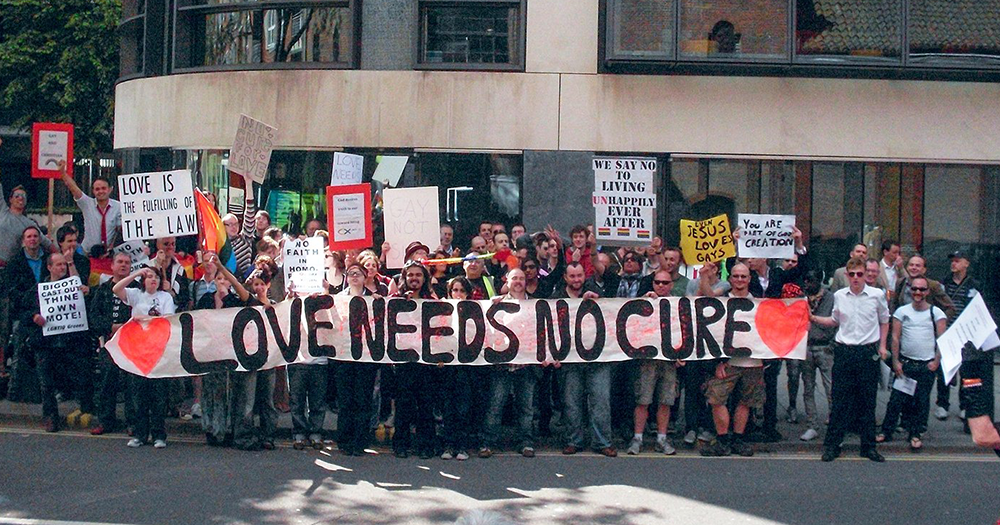 Conversion therapy protesters gather with a big sign saying 'love needs no cure' as the UK introduces plans to restrict the practice.