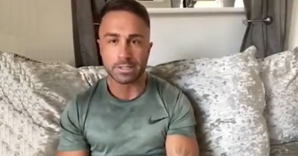 James Adcock sits on his sofa speaking to BBC about his experience being gay in football