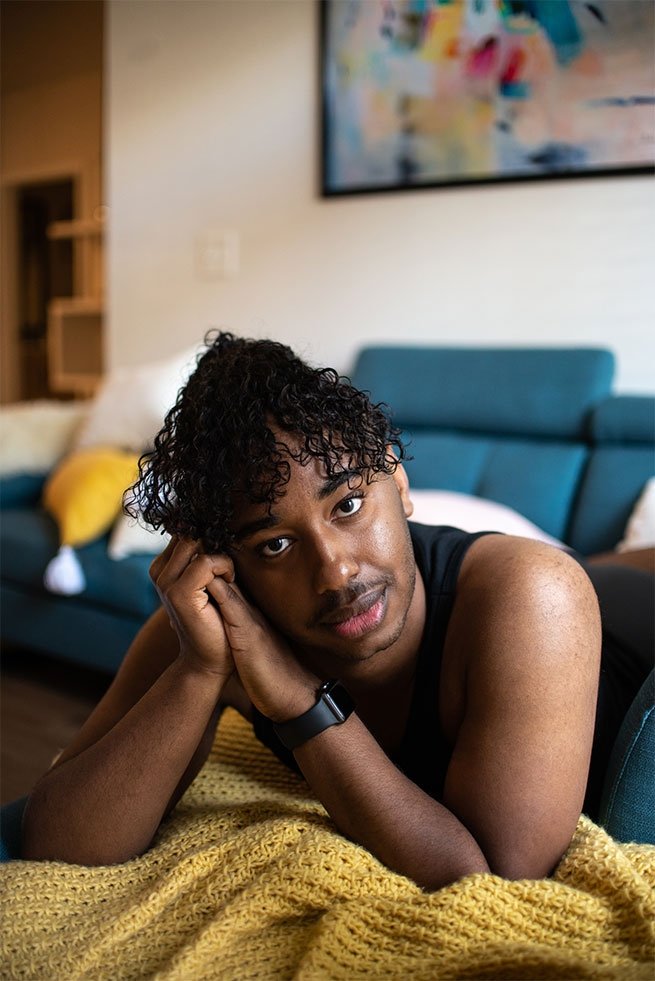 Portrait of a shirtless gay black man laying down in the latest edition of Elska