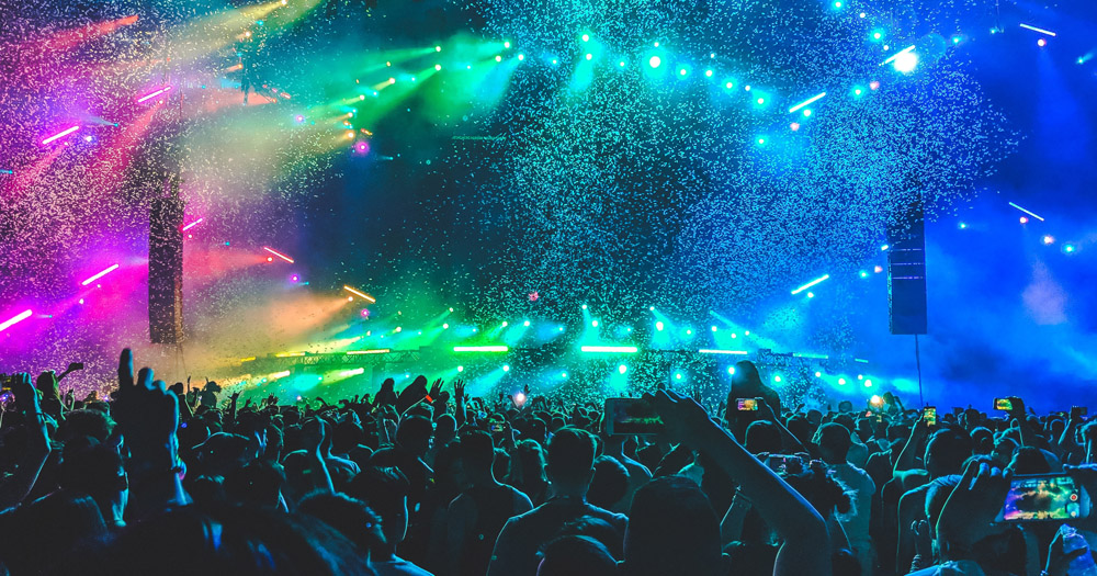 People at a pop music concert with colourful lights on stage.