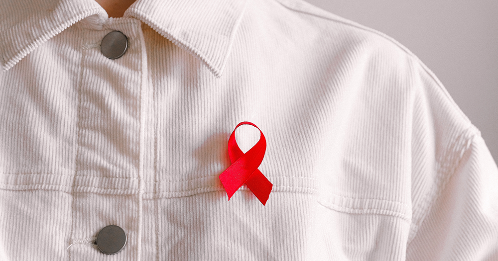 A person in a white jacket wears a red AIDS ribbon as the Gay Health Forum prepare for the 2021 event happening next week with a jam packed agenda.