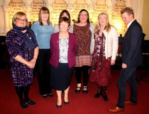 Seven people standing in a church with memorial scroll in background