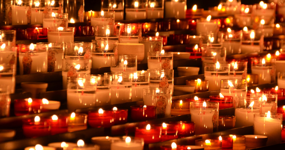 Image of approximately 50 red and white lighted church candles - Gender Ceremony of Remembrance