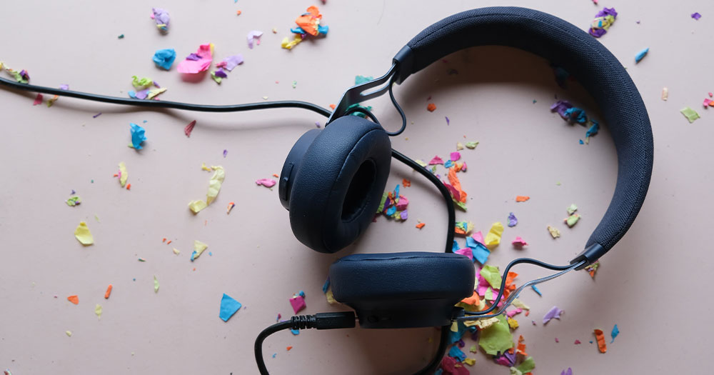 Black headphones laying on top of colorful confetti. These are 15 LGBTQ+ podcasts you need in your life.