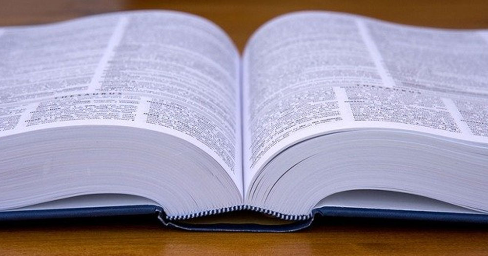An image of a dictionary laying open. You can see black text on white paper, as well as the spine of the book.