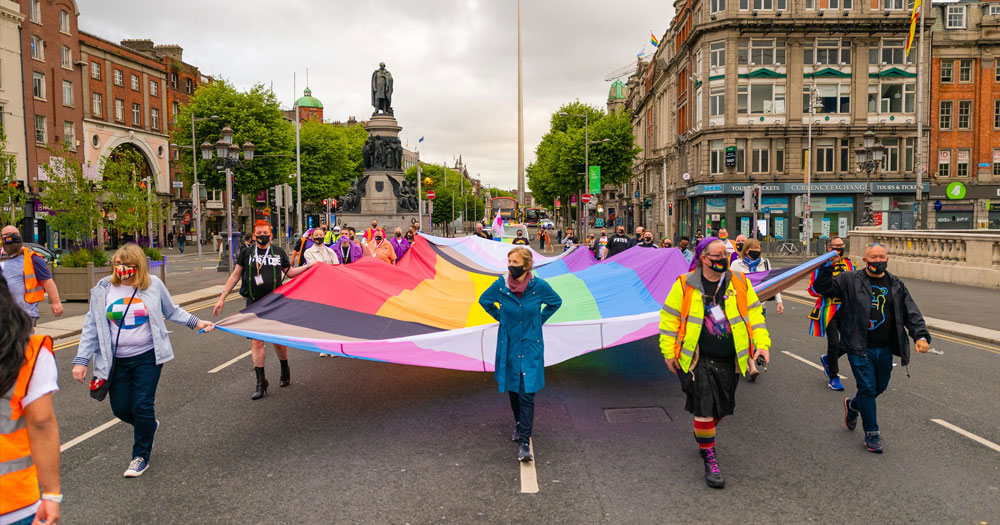 Dublin Pride carrying giant inclusive rainbow flag in Dublin