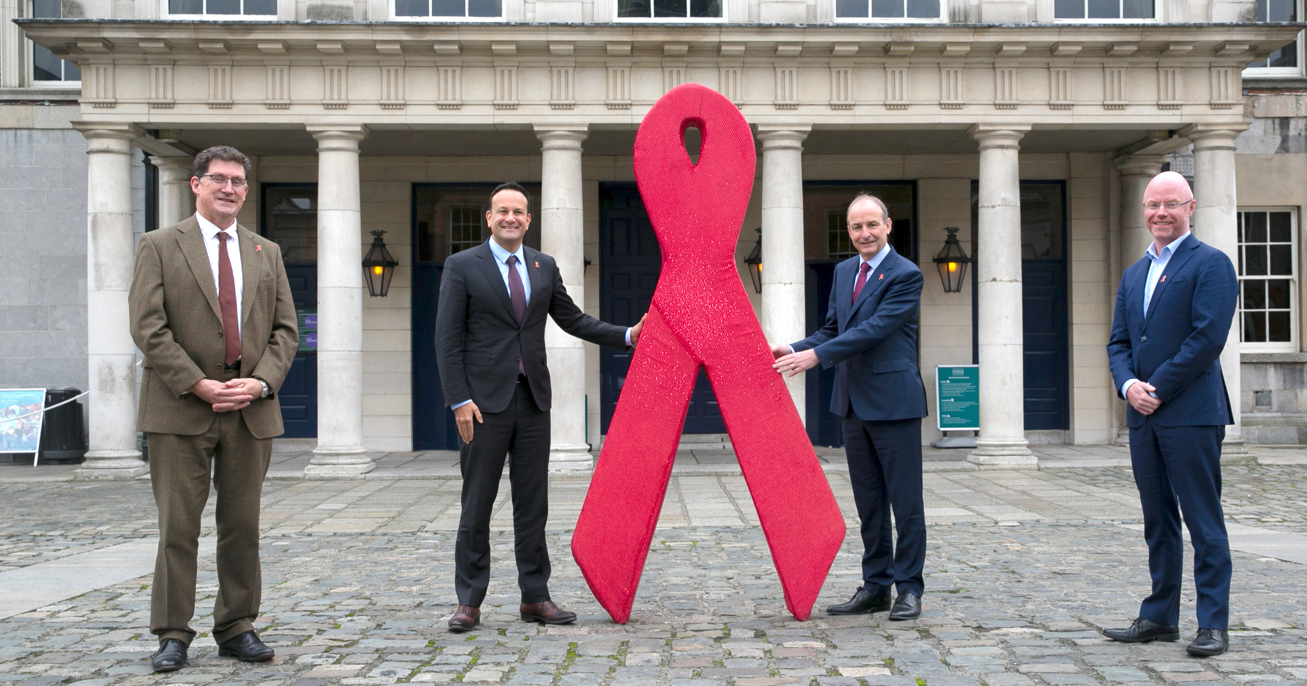 Government leaders pose with the red ribbon outside Dublin Castle for World AIDS Day 2021.