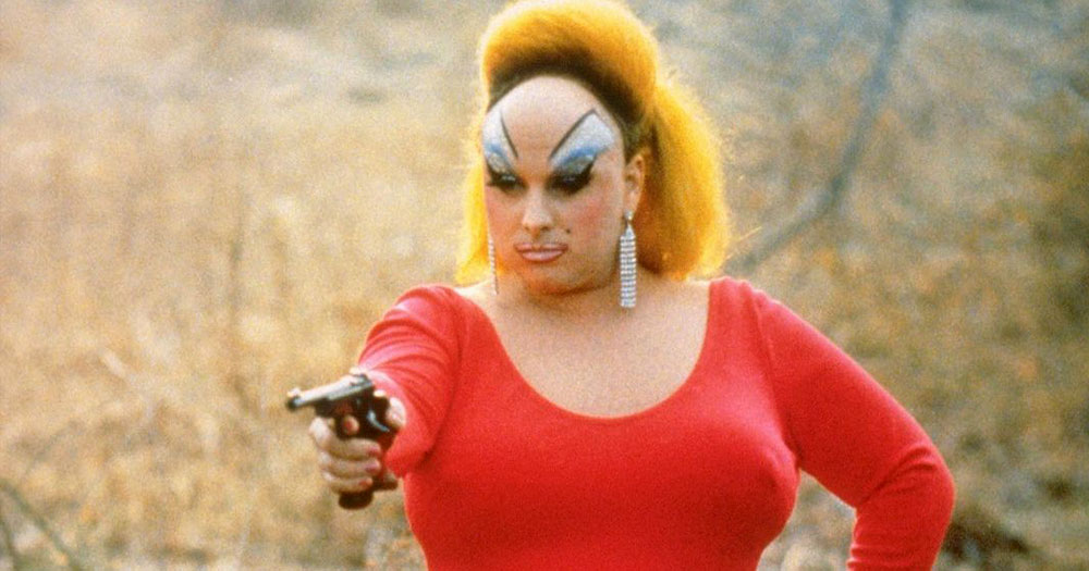 A flamboyant drag queen pointing a gun