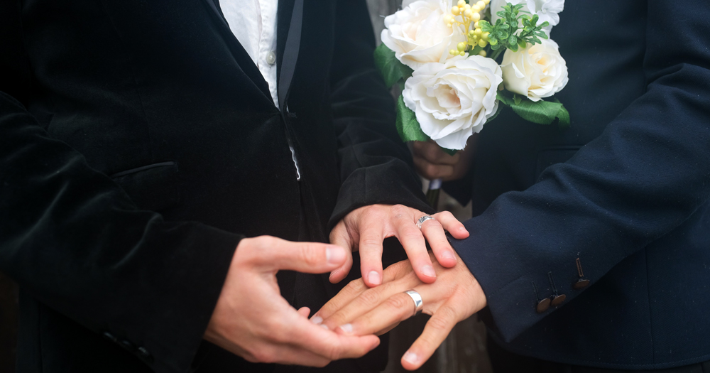 The hands of two men getting married