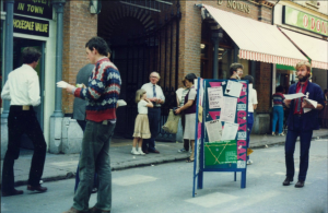 Colour photo of men handing out fliers.