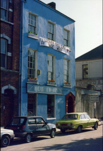 Photo of a three storey blue building with a white banner hung across the second floor which reads, Lesbian and Gay Pride Week.