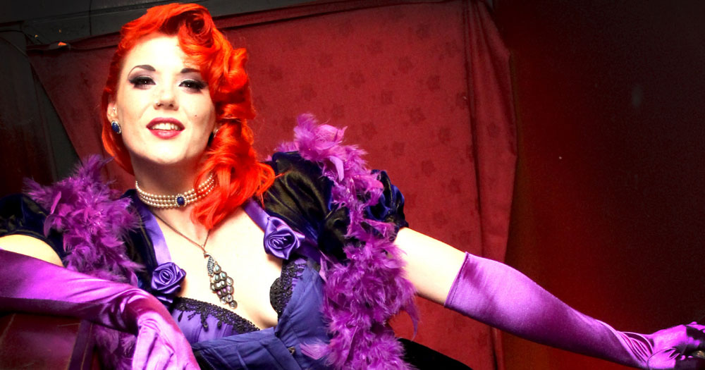 Red-haired burlesque dancer wearing purple on the poster for queer night of cabaret