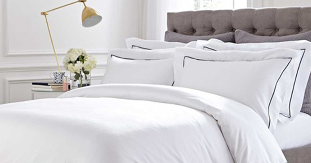 A bed with white linens and pillows representing a Valentine's sleep hamper giveaway.