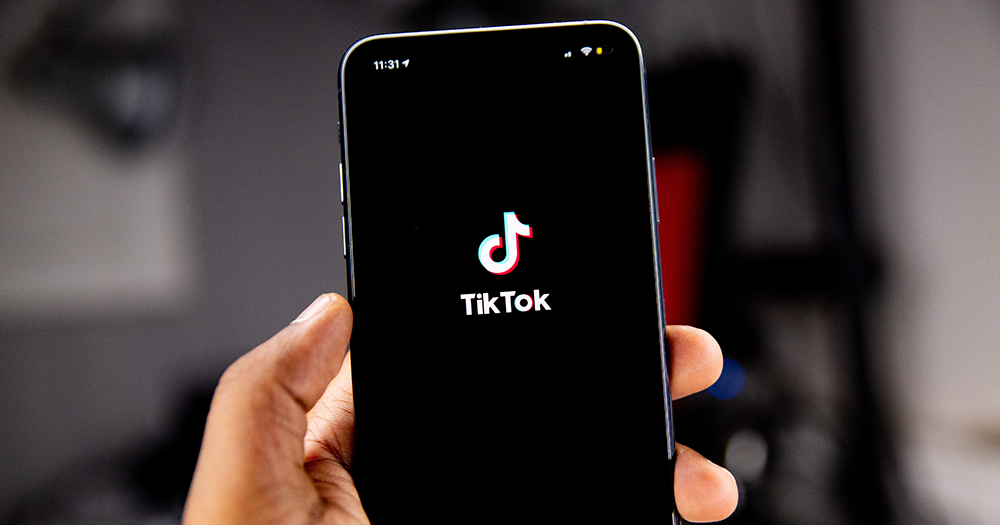 A person holds their phone with TikTok on the screen as the app updates its community guidelines.