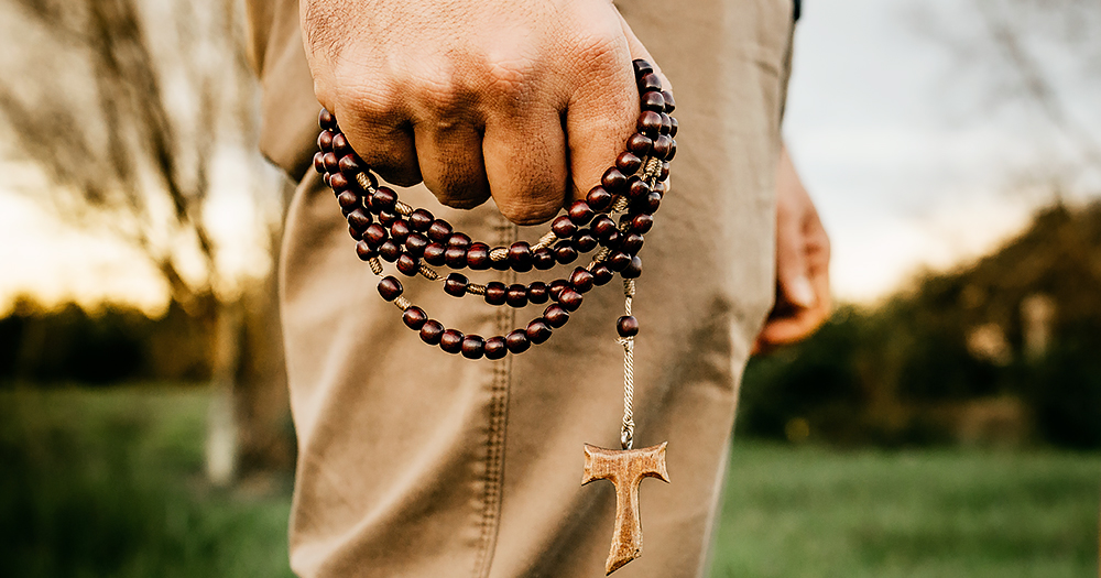 The hand of a man holding a rosary. This article is about a Virginia bill for religious exemptions.