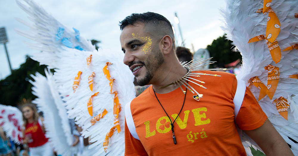 A smiling man with face paint and feathered angel wings
