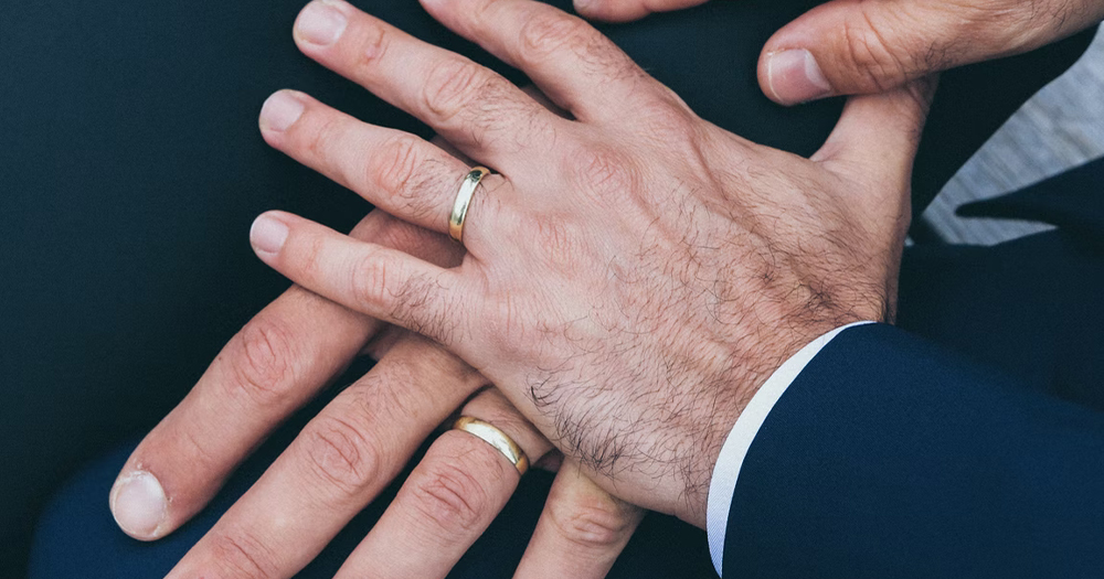 A same-sex couple's hands at a wedding as the Cayman Islands and Bermuda ban the practice.