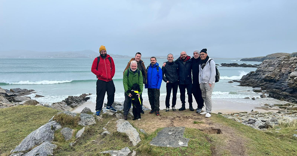 Members of the Donegal Gay Walking Group pose on a cliff overlooking the coast.